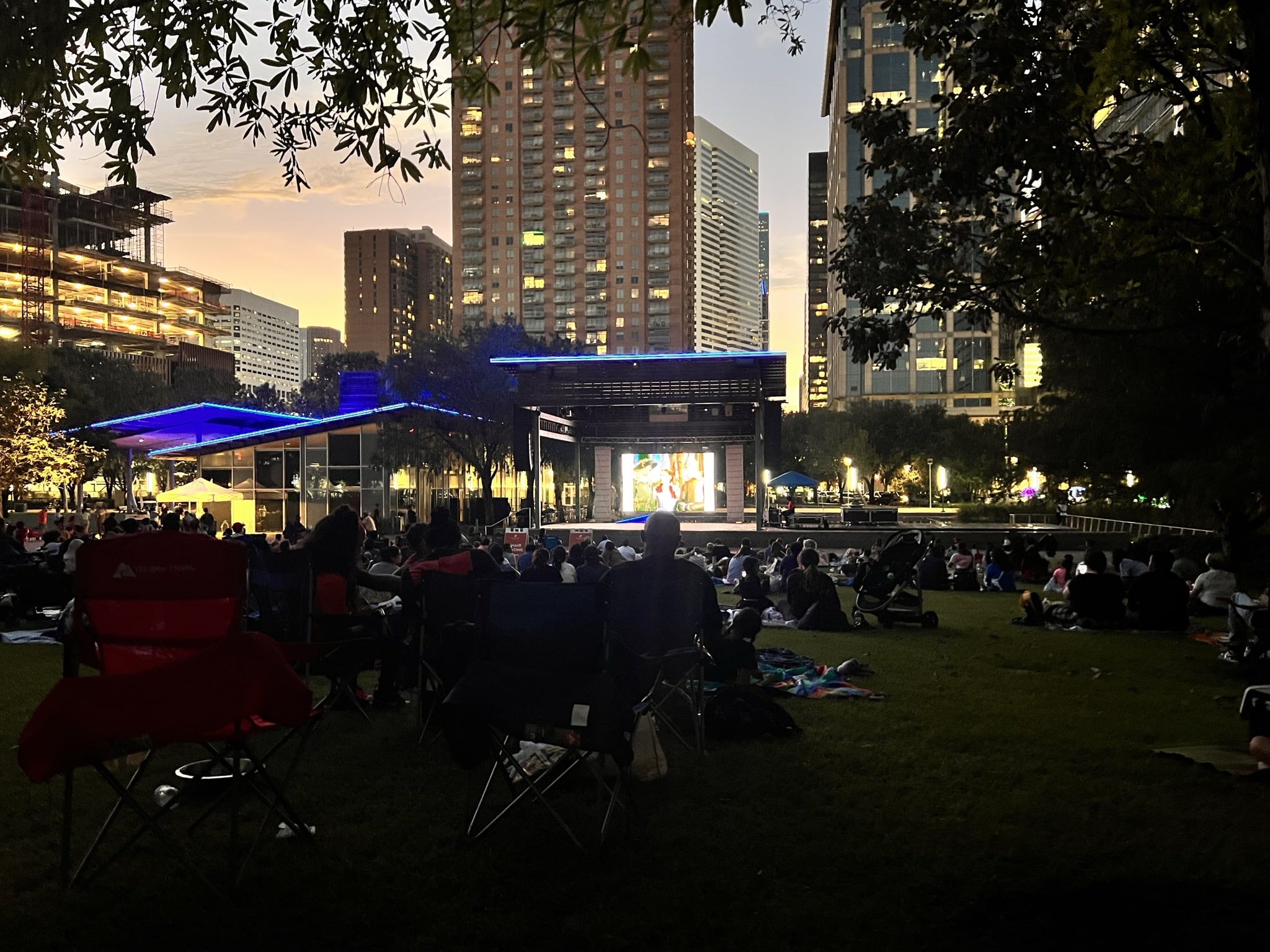 People watch a movie under the night sky at Discovery Green