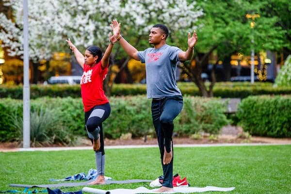 A man and a woman practicing Hatha Yoga at Discovery Green in Downtown Houston