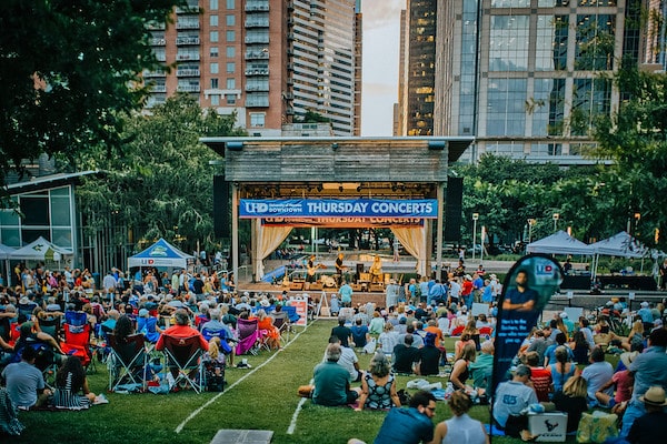 A crowd of people enjoying an outdoor concert at Discovery Green in Downtown Houston
