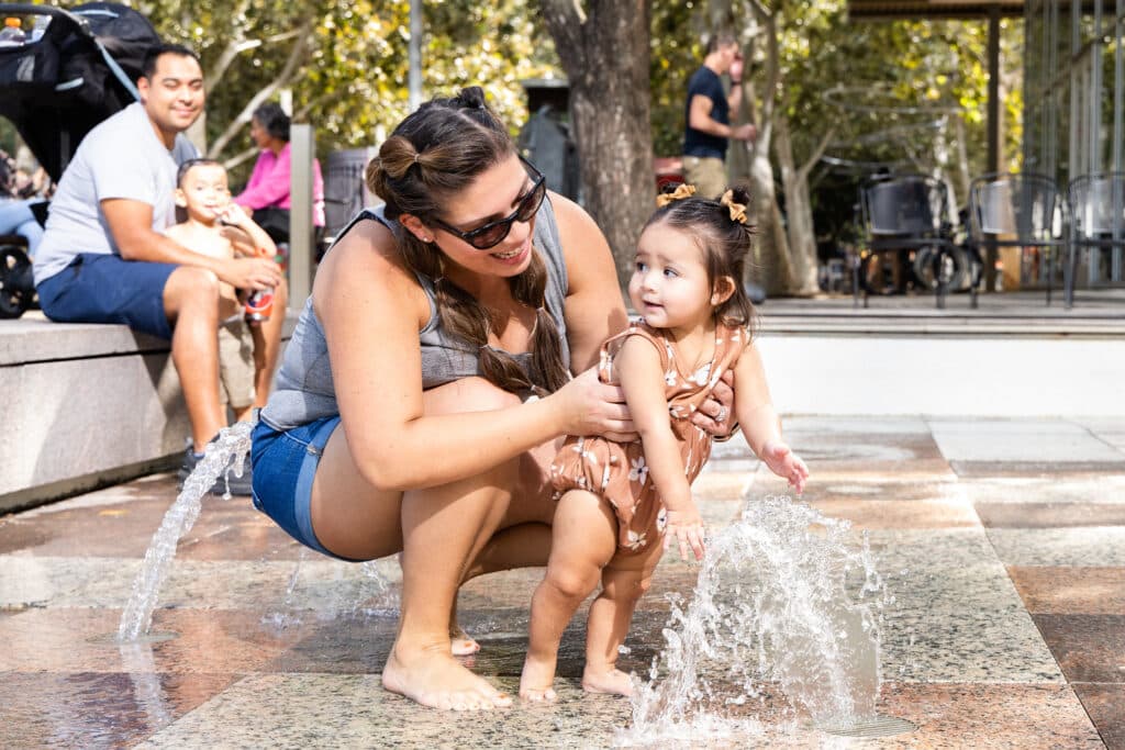 A mother and daughter play in the Gateway Fountains at Discovery Green