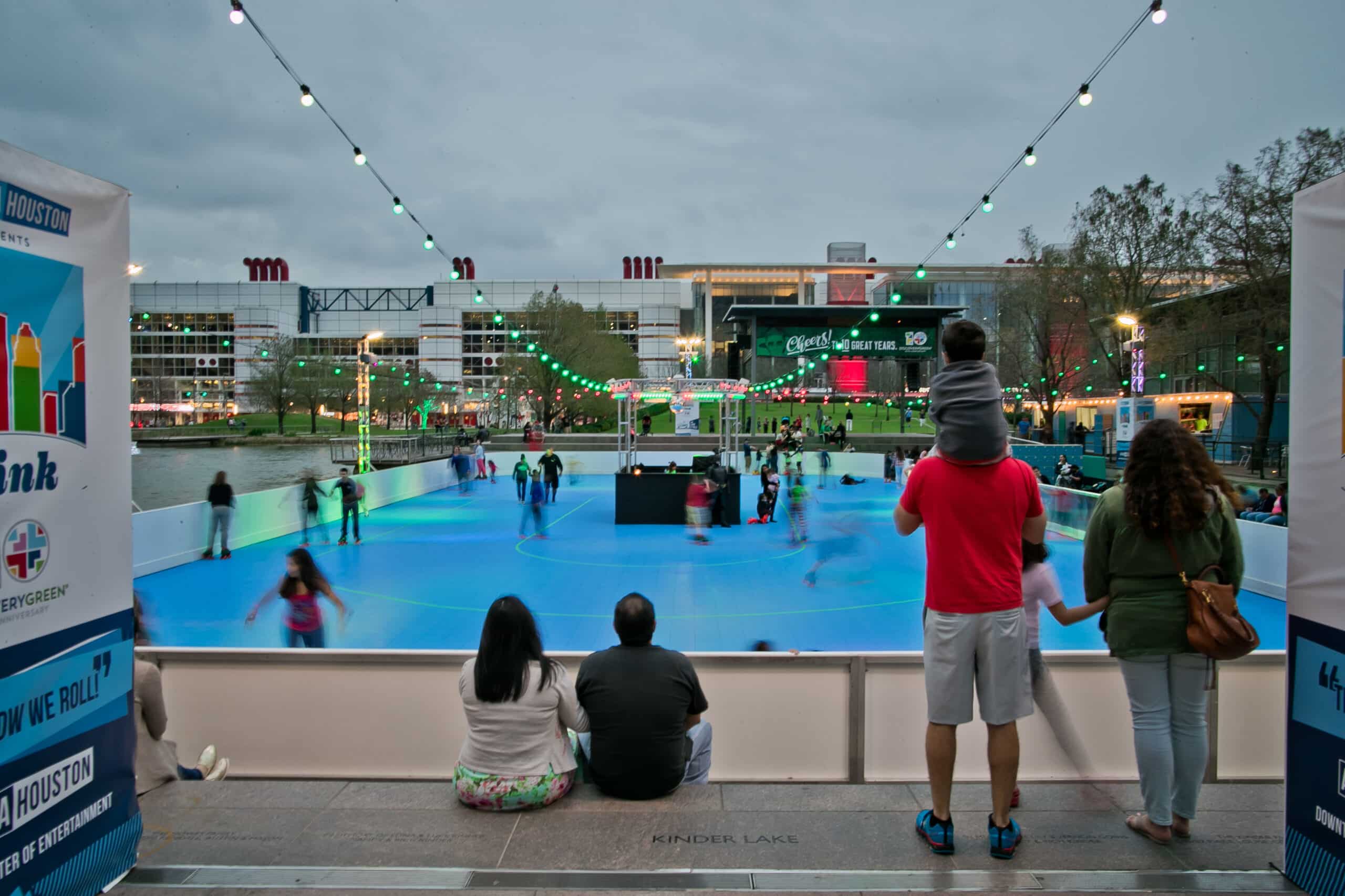 A couple and a family gazing at skaters on the roller rink in Downtown Houston