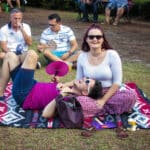 A man and a woman lounge on a blanket on the lawn at Rainbow on the Green at Discovery Green