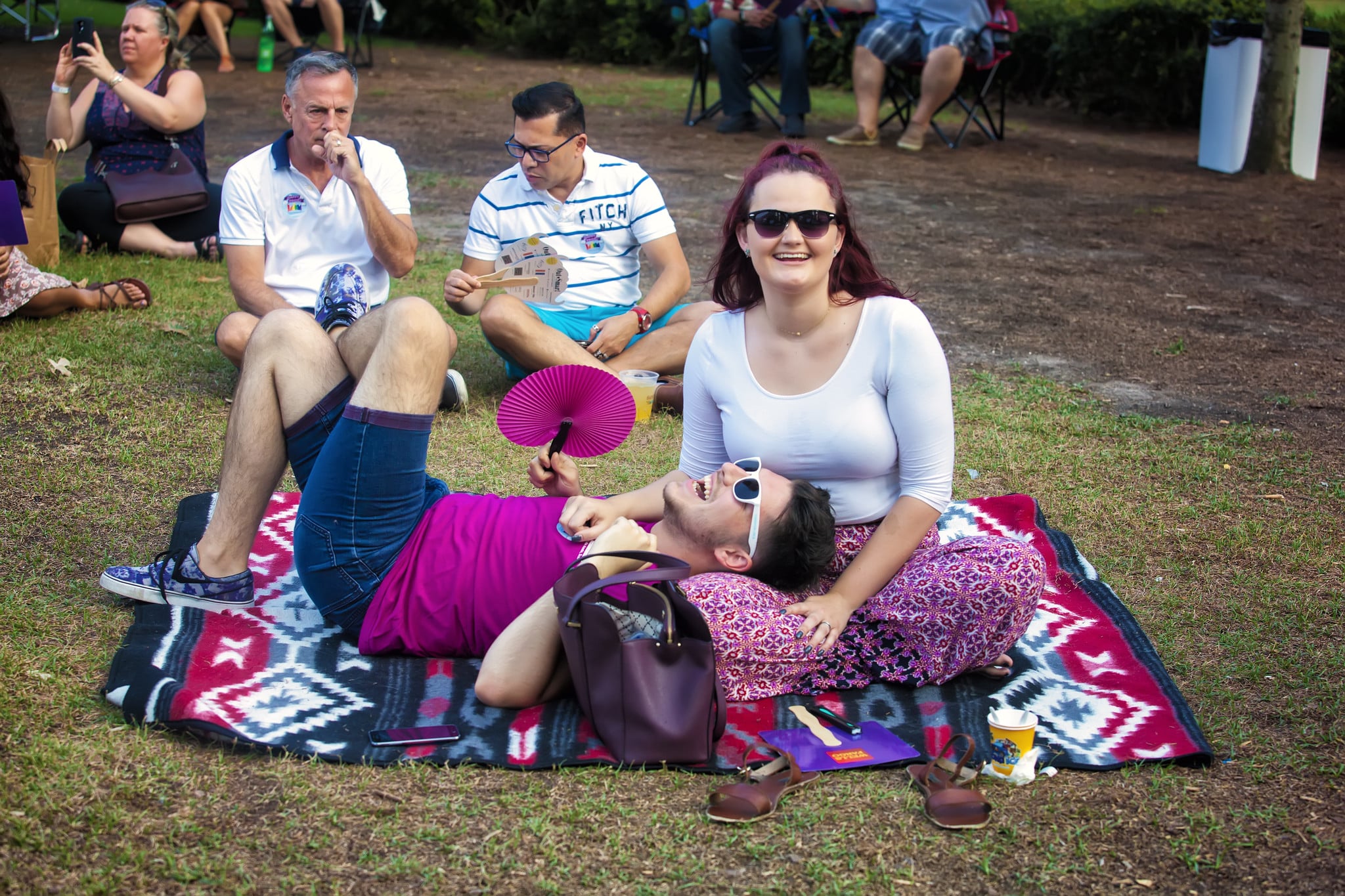 A man and a woman lounge on a blanket on the lawn at Rainbow on the Green at Discovery Green