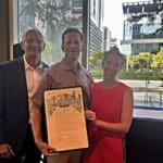 Robert Gallegos, Barry Mandel and Abbie Kamin pose for a photo with the Barry Mandel Day proclamation at Discovery Green in downtown Houston