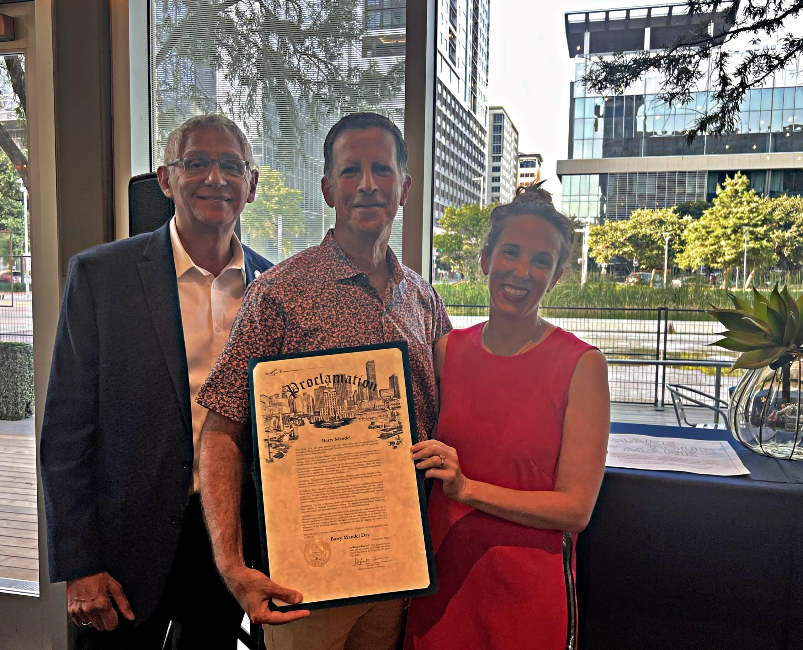 Robert Gallegos, Barry Mandel and Abbie Kamin pose for a photo with the Barry Mandel Day proclamation at Discovery Green in downtown Houston