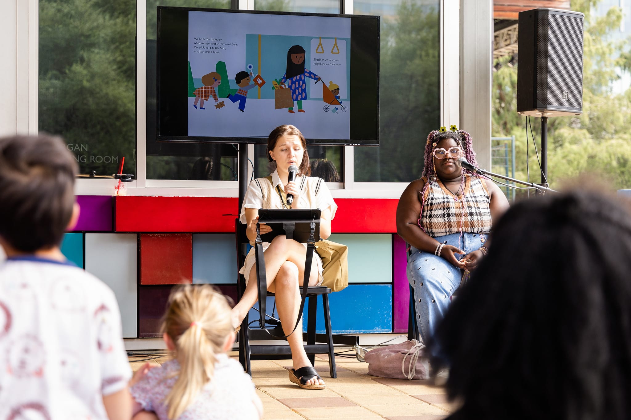Two women read a book aloud to toddlers during an event at Discovery Green