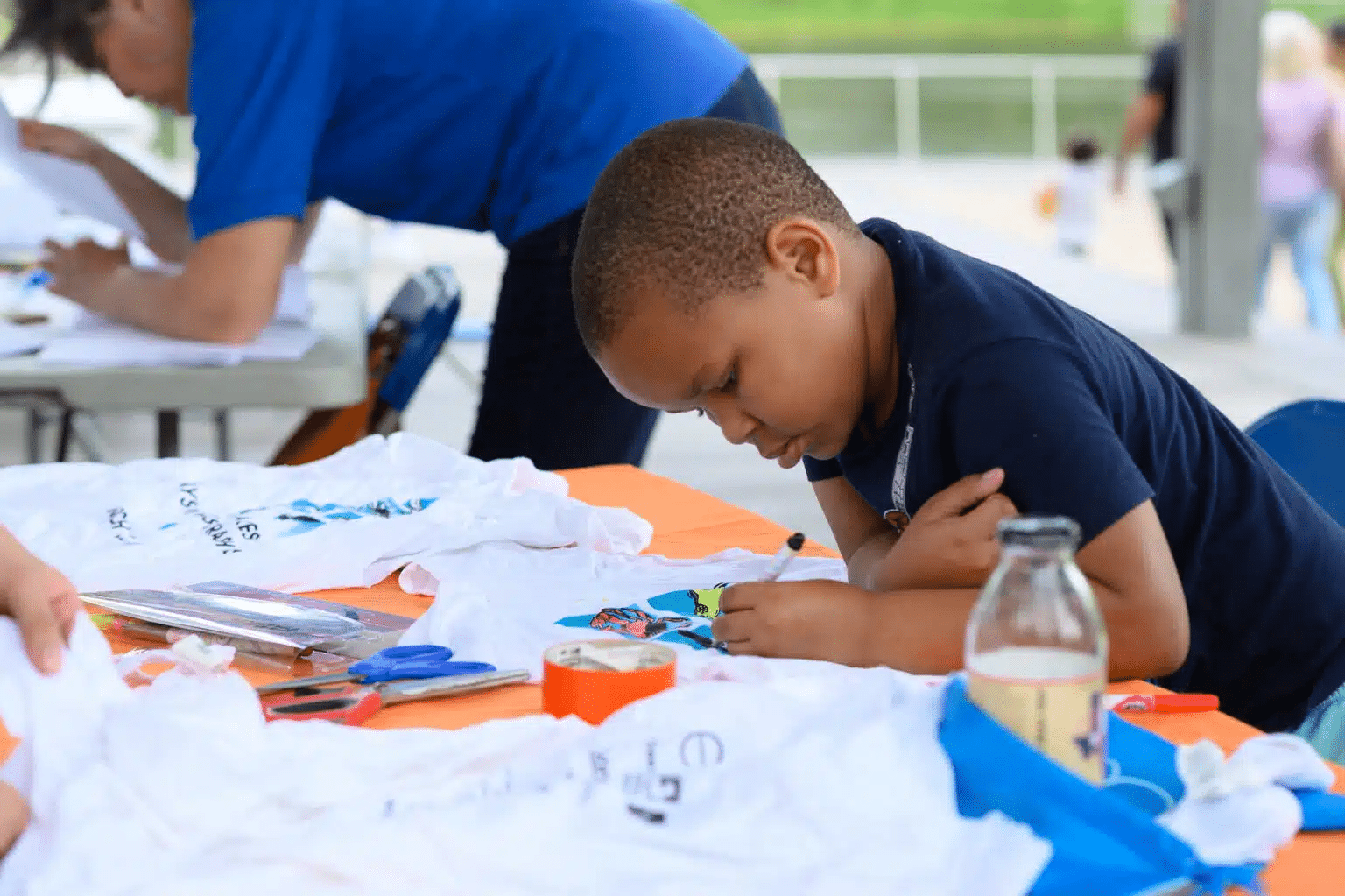 Young child performs arts activity outside.